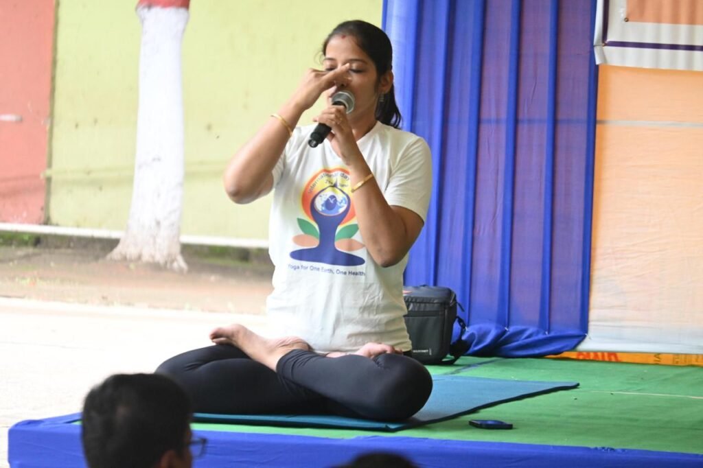 Yoga instructor demonstrating Nadi Shodhana pranayama while seated in Padmasana during a public yoga session